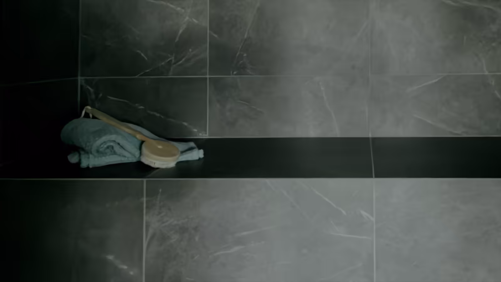 Mörkt kaklat badrum med handduk och borste